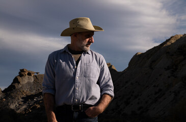 Adult man in cowboy hat standing against mountains in Tabernas desert. Almeria, Spain