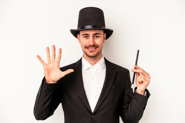 Young caucasian wizard man holding a wand isolated on white background smiling cheerful showing number five with fingers.