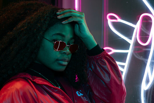 Stylish girl standing in the night on the street. Illuminated signboards, neon, lights