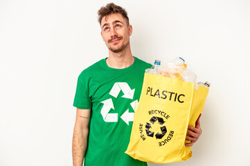 Young caucasian man recycled plastic isolated on white background dreaming of achieving goals and...