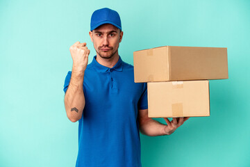 Young delivery caucasian man isolated on blue background showing fist to camera, aggressive facial expression.