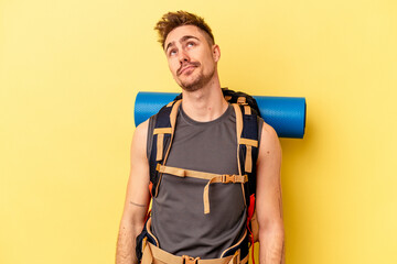 Young hiker caucasian man isolated on yellow background dreaming of achieving goals and purposes