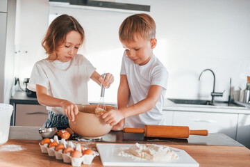 Preparing food together. Little boy and girl on the kitchen