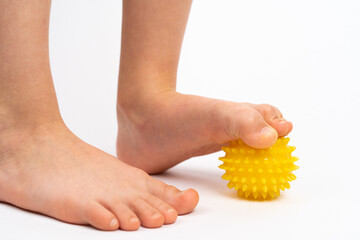 Obraz premium yellow needle ball for massage and physical therapy on a white background with a child's foot, the concept of prevention and treatment of foot valgus