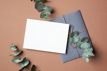 Invitation or greeting card mockup with envelope and natural eucalyptus twigs.