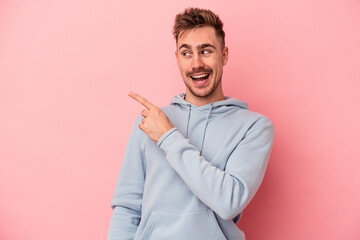 Young caucasian man isolated on pink background looks aside smiling, cheerful and pleasant.