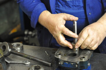 The hands of a working locksmith assemble a water pump