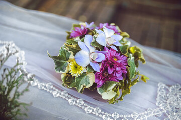 bride's bouquet of lilac orchids and purple asters with wedding rings on orchids against the background of the bride's veil
