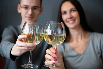 a young couple tasting white wine,close up of hands holding glass