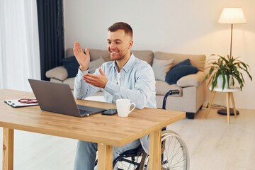 Laptop on the table. Disabled man in wheelchair is at home