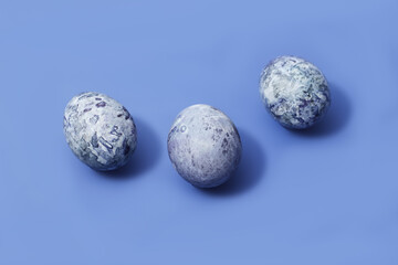 Three easter marbled purple eggs on blue background