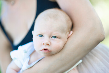 Close-up of a newborn baby's face, which the mother holds on her hands