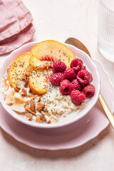 Porridge oatmeal with raspberries, peaches and nuts for breakfast. Healthy vegetarian food concept.