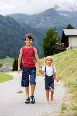 Happy family in Switzerland, walking on a mountain little road, going on vacation