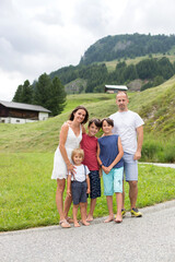 Fototapeta na wymiar Happy family in Switzerland, walking on a mountain little road, going on vacation