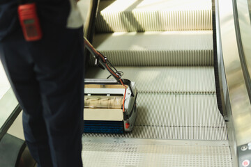 Male cleaner cleaning escalator with mechine in modern building.