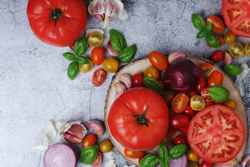 Flat lay composition of different tomatoes, onion, basil and garlic	
