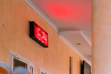 A red digital board on the wall shows time 16:24. Date. Red led electronic scoreboard indoor....