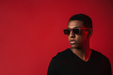 Young black man wearing sunglasses posing and looking aside