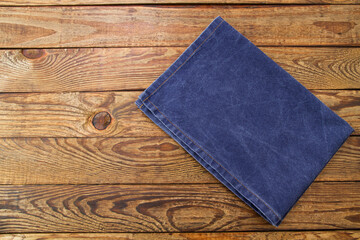 Closeup jeans tablecloth on wooden background. Dark blue table cloth on brown wood textured tabletop. Mock up and copy space. Kitchen workspace flat lay, top view. Cooking workplace. Thanksgiving day