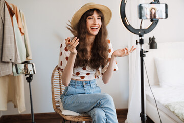 White woman smiling while taking selfie footage on cellphones