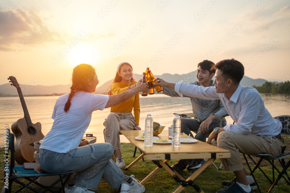 Wall mural happy group of Asian friends Play guitar and sing enjoying camping and drinking beer