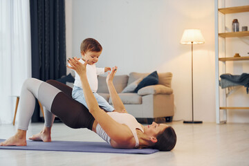 Obraz premium Doing fitness together. Mother with her little daughter is at home together
