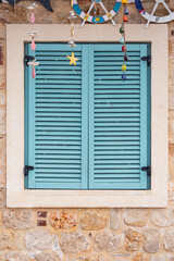 Close-up of a blue wooden vintage window in an old stone house with nautical decorations