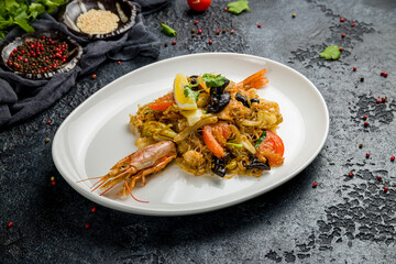 Rice noodles with shrimp and vegetables on dark stone table, Chinese cuisine
