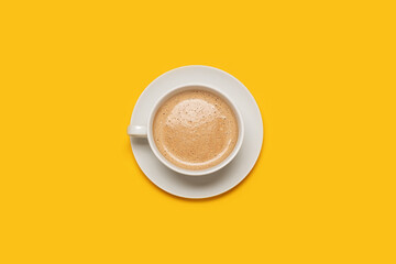 single cup of coffee with foam in a white cup on a yellow background with copy space and room for text with a center composition