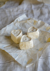 Fototapeta na wymiar Heart-shaped cheese with white mold on wrapping paper. Home production, natural products.
