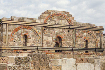 Fototapeta na wymiar Sights of ancient Side, Turkey. Two-story building with arched windows. Fragments of stone walls.