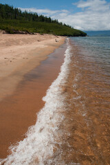 Sandy shore and oncoming wave on Lake Baikal in Irkutsk region in Russia