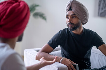 Two men in turbans talking and looking involved