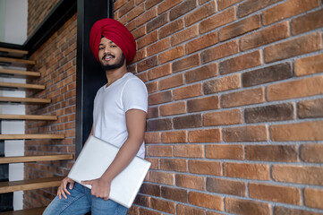 Young indian man in red turban standing on stairs