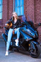 Fototapeta na wymiar Motor Cycling Concepts. Beautiful Caucasian Female Biker Girl In Leather Jacket and Helmet on New Motorbike Outdoors Against Grunge Background