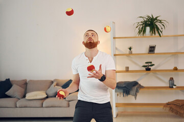 A man in casual clothes throws balls at home