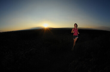 Fototapeta na wymiar Woman jogger over lava field at sunrise, Big Island, Hawaii, USA, MR