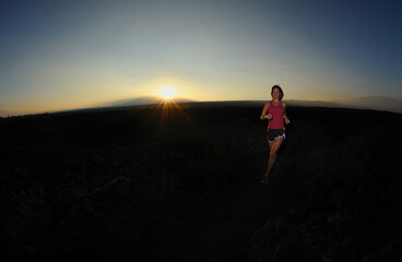 Woman jogger over lava field at sunrise, Big Island, Hawaii, USA, MR