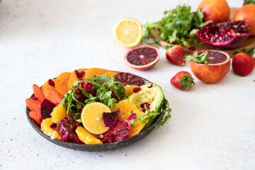 Healthy vegetarian buddha bowl salad with blood orang ,persimmon, arugula, avocado and pomegranate seeds.