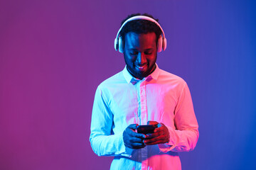 Young black man listening music with headphones and cellphone