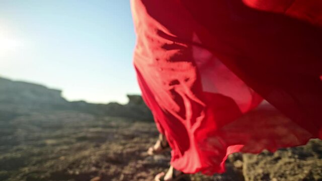 Close-up of red dress fabric on Caucasian attractive woman ripples in the wind. Walk on the sea in windy weather