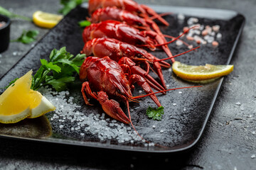 Boiled crawfish with lemon and herbs on a slate plate ready to eat on black background. lemon juice, Healthy food