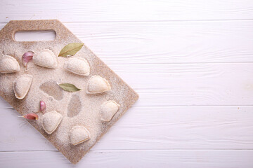 Raw dumplings with cabbage on white wooden background with place for text. Vareniki is a dish of Slavic cuisine. Top view.