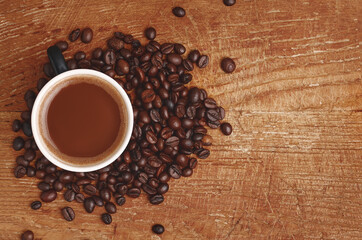 Cup with coffee drink and coffee beans on wooden background. Copy space