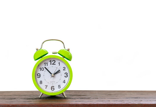 Green alarm clock on wooden desk isolate white background.