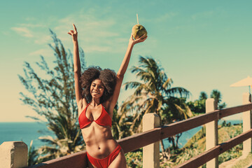 A dazzling happy young Brazilian female with curly fluffy afro hair is enjoying a sunny day on a...