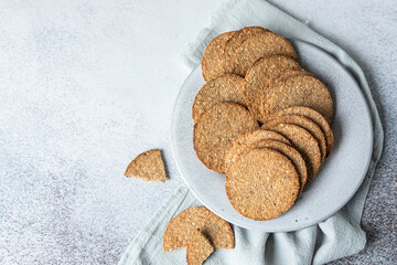 Plate with tasty crackers with sesame and flax seeds on grey background. Top view.