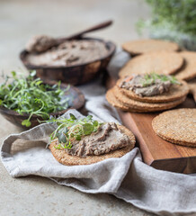 Homemade meat or chicken liver pate with multigrain crackers and microgreen.