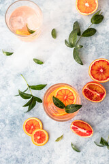 Gin and tonic alcohol drink with blood Sicilian oranges and ice on blue background. Cold refreshing...
